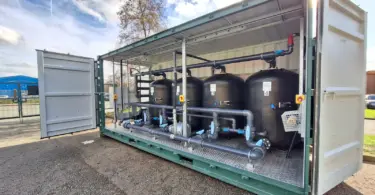 Flocell XFM modular filtration system featuring four filtration vessels, pipework and valves housed inside an open-sided container.