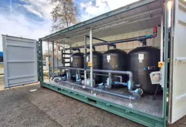 Flocell XFM modular filtration system featuring four filtration vessels, pipework and valves housed inside an open-sided container.