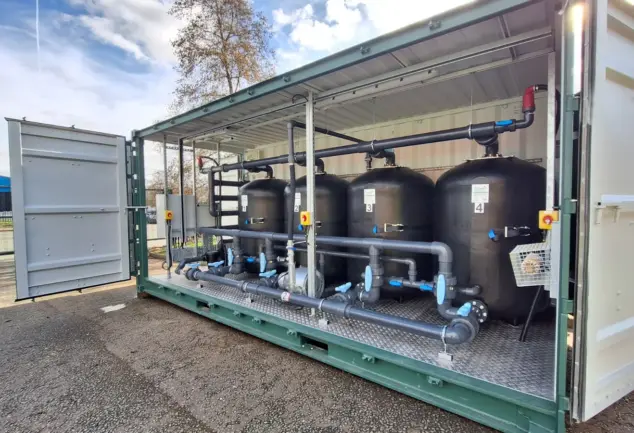 Flocell XFM modular filtration system featuring four filtration vessels, pipework and valves housed inside an open-sided container.