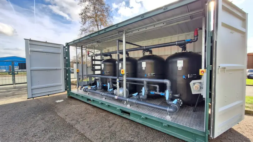 Flocell XFM modular filtration system featuring four filtration vessels, pipework and valves housed inside an open-sided container.