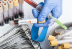 A scientist's hand holding a test tube containing a blood sample for a Legionella test.