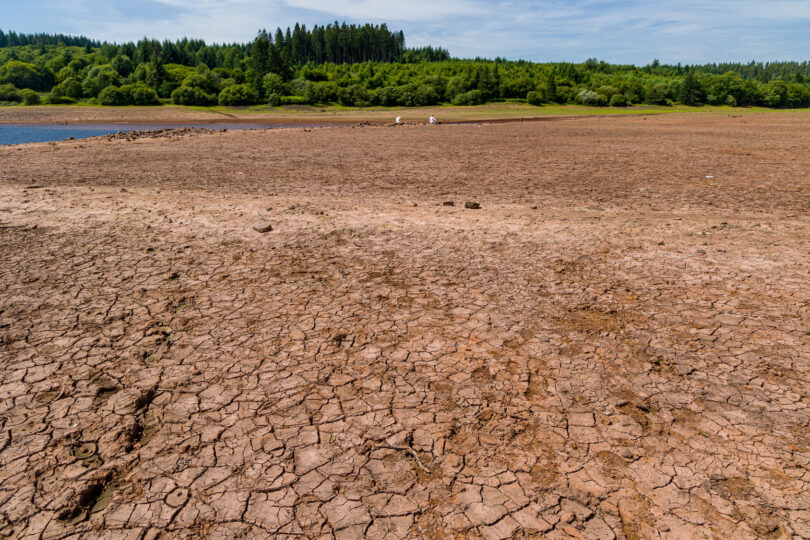 Baked, cracked, dry soil at a near-empty reservoir during a heatwave and drought.