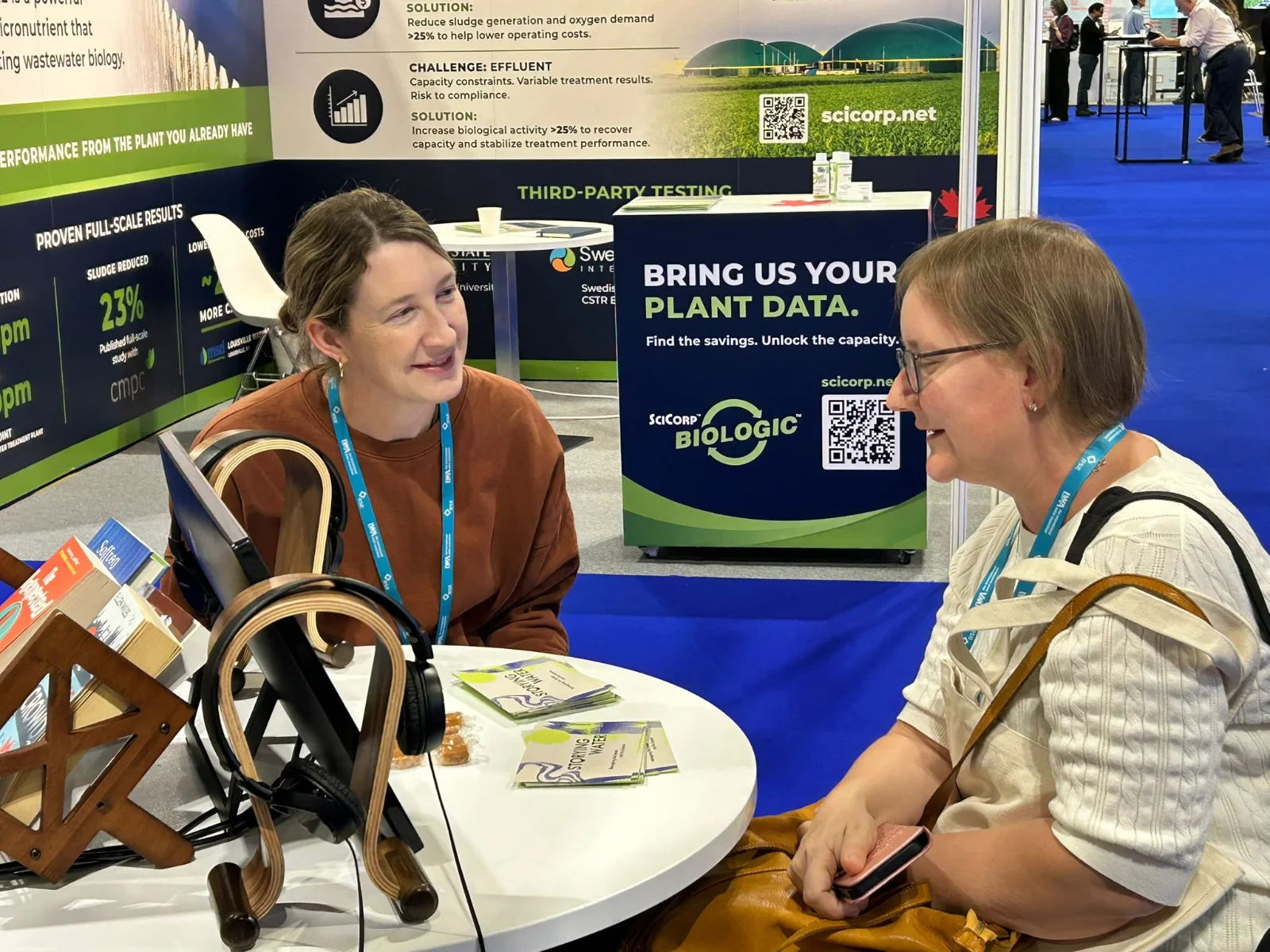 Two women discussing the Storying Water audio project at an exhibition table during the IWA World Water Congress