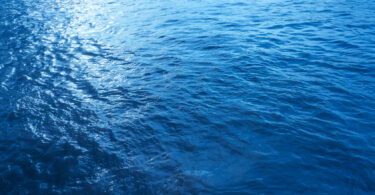 Close-up, low-angle view of a blue sea wave, used as a summer background image.