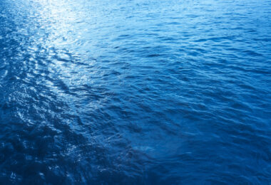 Close-up, low-angle view of a blue sea wave, used as a summer background image.