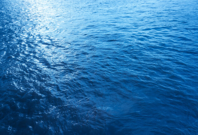 Close-up, low-angle view of a blue sea wave, used as a summer background image.