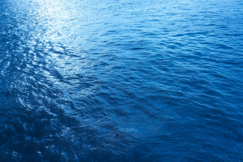 Close-up, low-angle view of a blue sea wave, used as a summer background image.